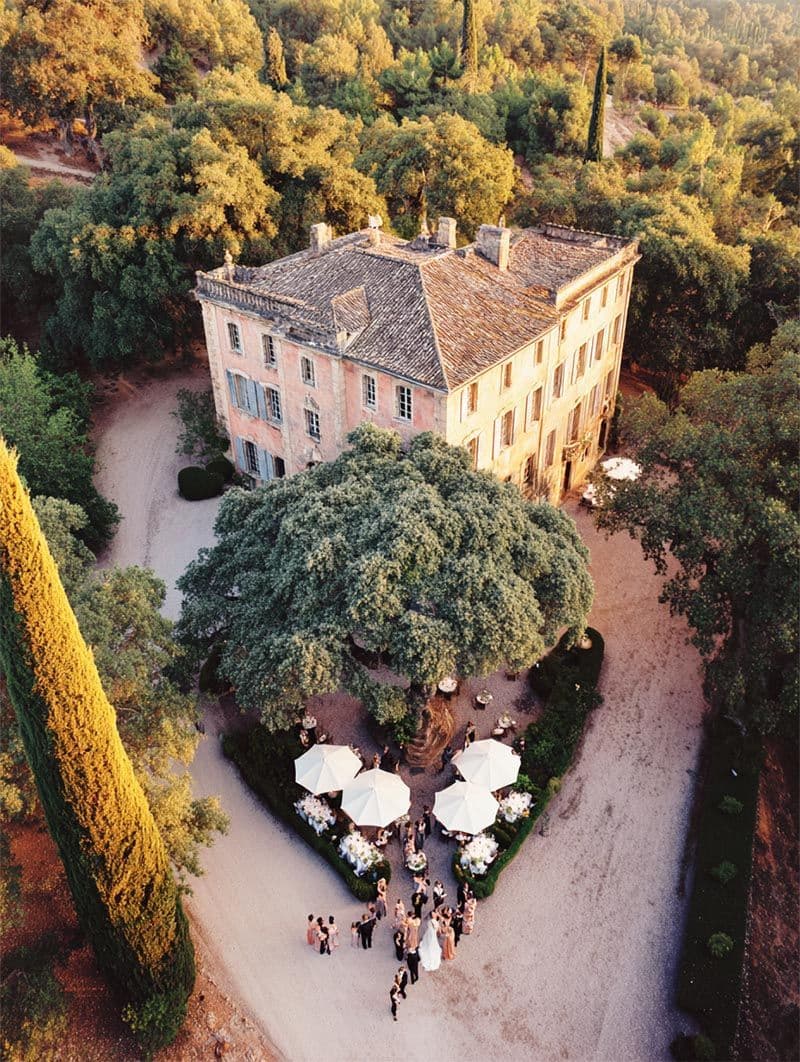 Guests mingling in French château gardens at twilight, destination wedding scene by Michigan Luxury Weddings
